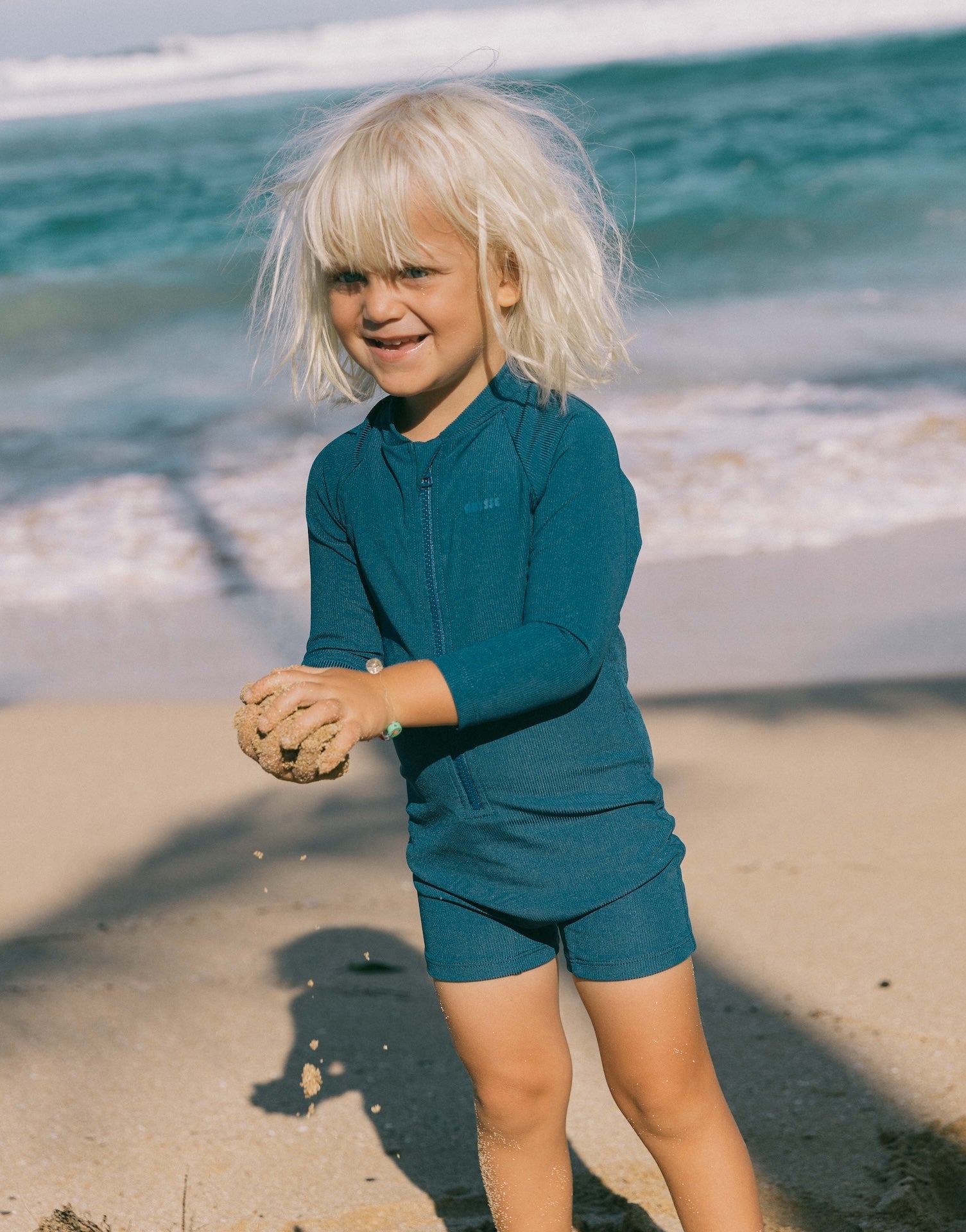 Introducing the Mini Dekker Surf suit, a long sleeve one-piece rash guard, with boy cut shortie bottom.