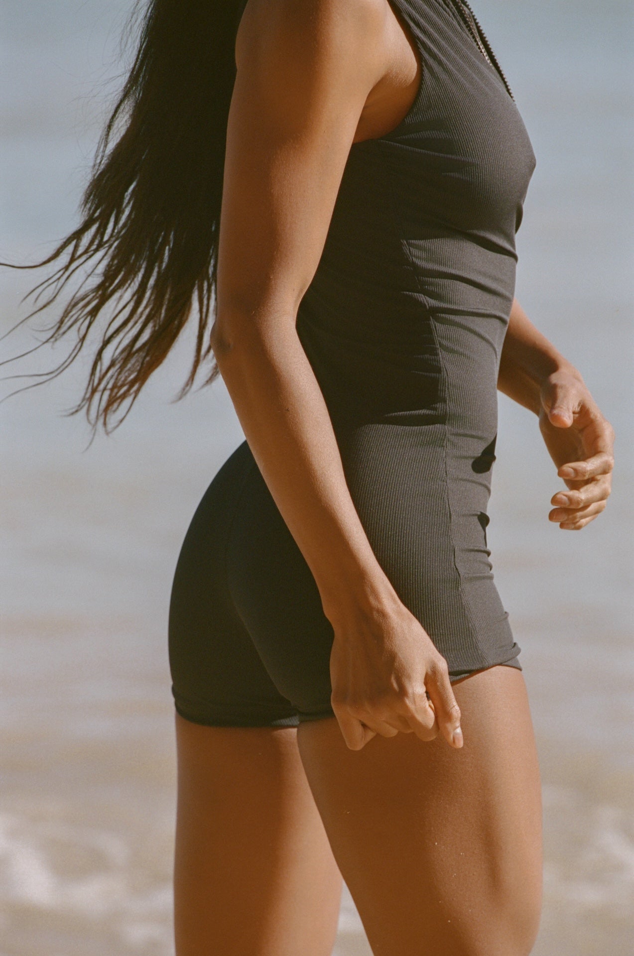 Person wearing a black tank top and shorts on a beach