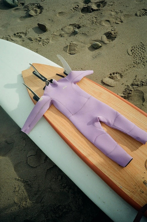 Purple wetsuit on a wooden board with sand in the background