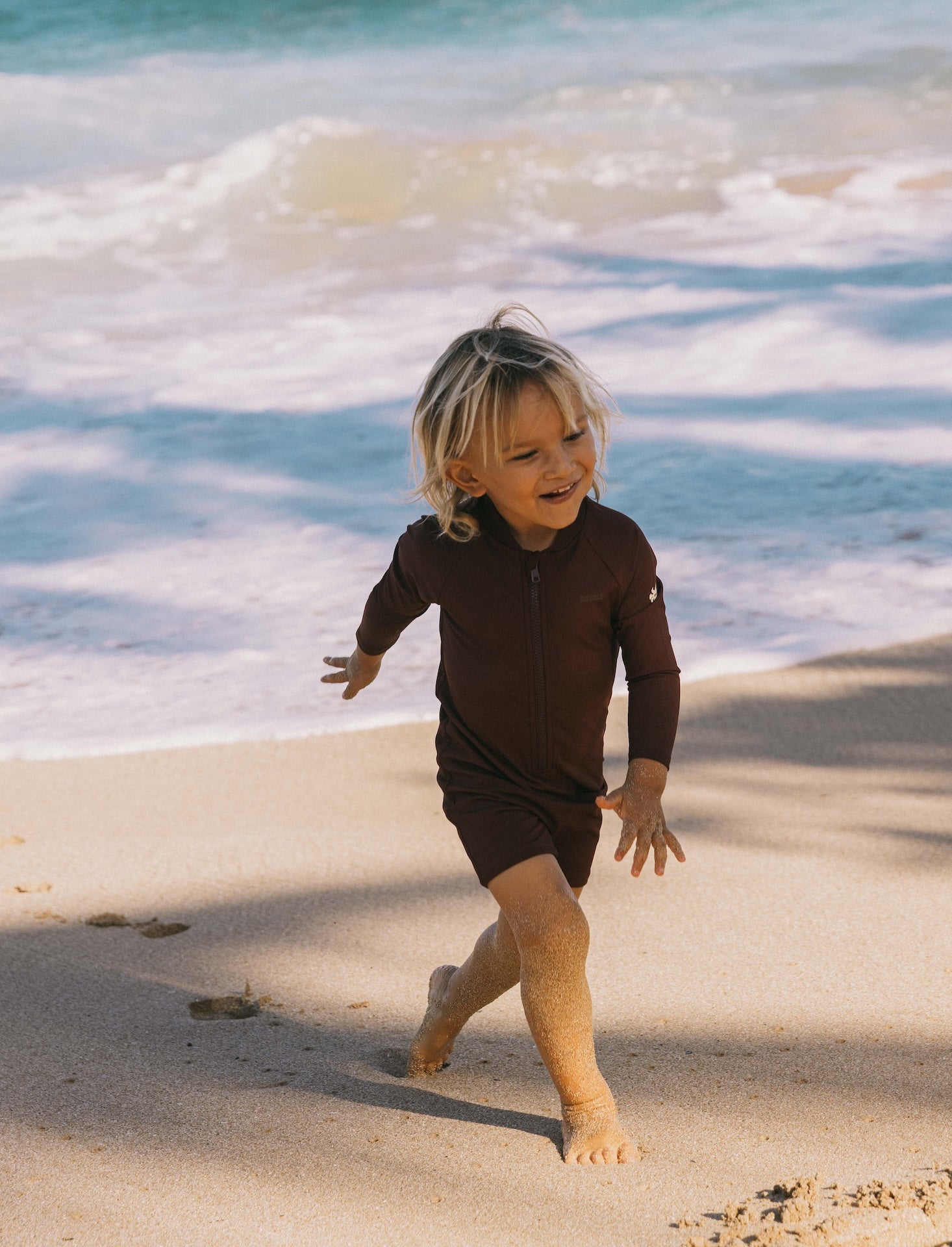 Introducing the Mini Dekker Surf suit, a long sleeve one-piece rash guard, with boy cut shortie bottom
