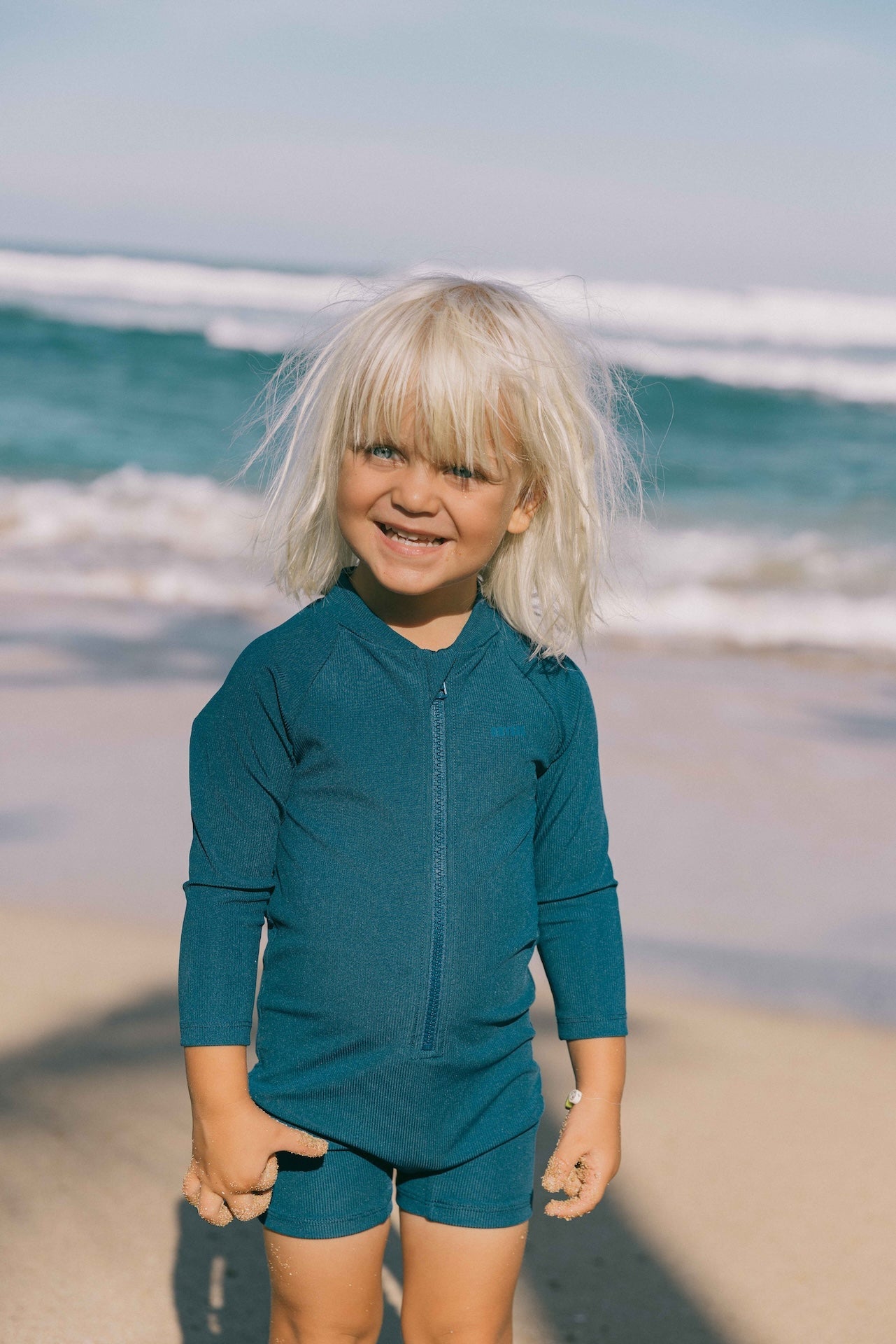 Introducing the Mini Dekker Surf suit, a long sleeve one-piece rash guard, with boy cut shortie bottom.