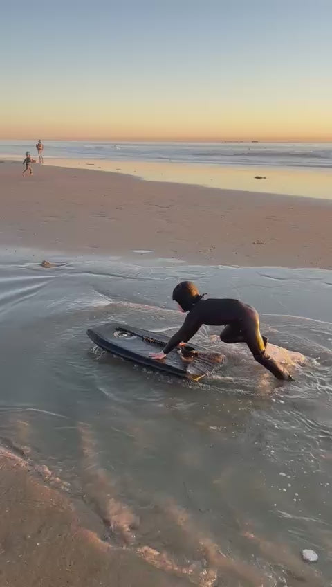 Child in a black wetsuit playing in the water